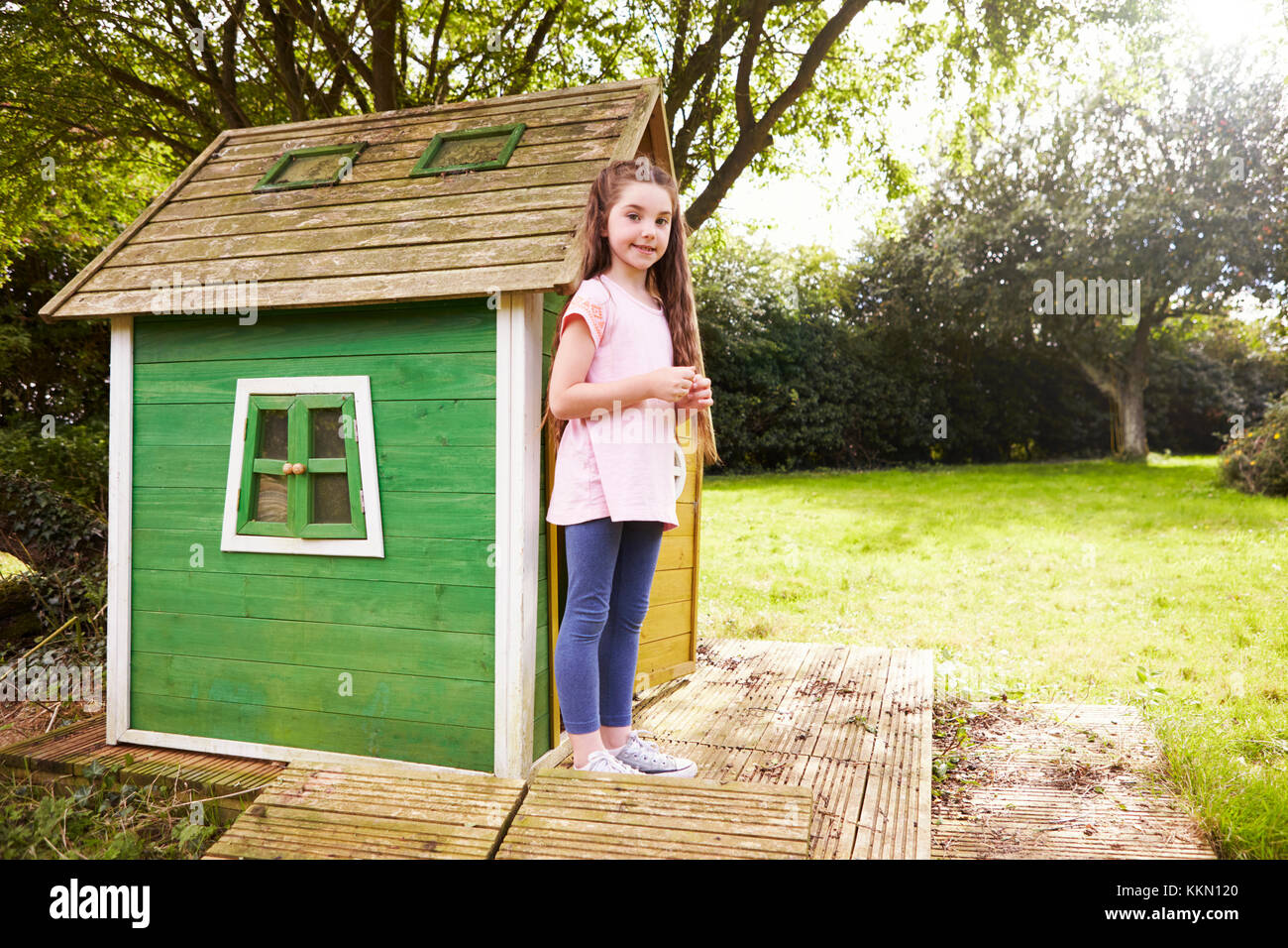 Ritratto di ragazza in piedi in giardino accanto al Playhouse Foto Stock