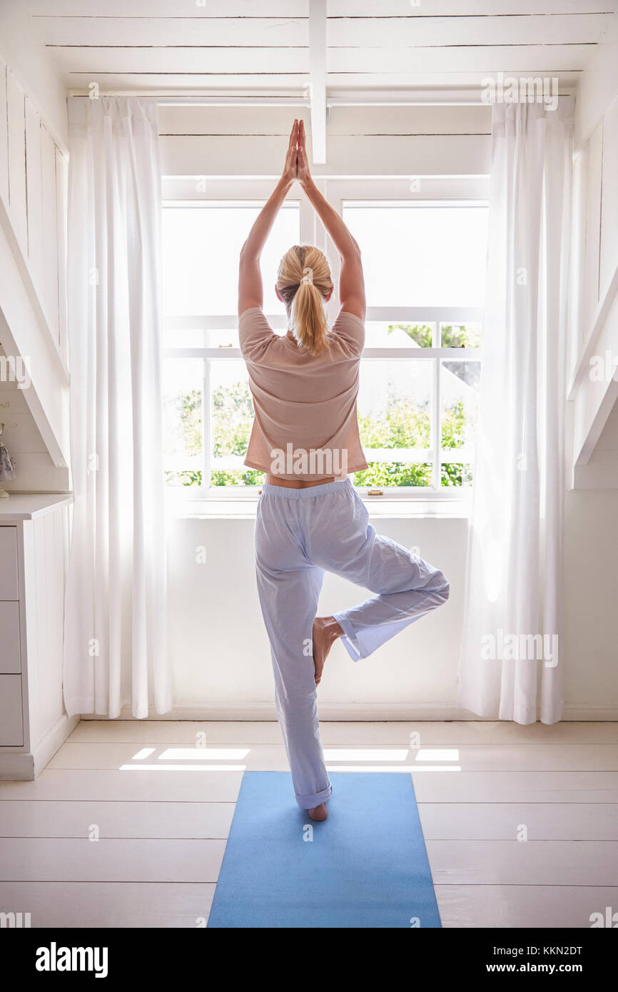 La donna a casa la mattina partenza con esercizi di yoga in camera da letto Foto Stock
