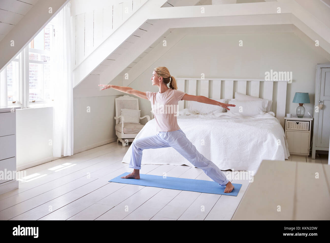 La donna a casa la mattina partenza con esercizi di yoga in camera da letto Foto Stock