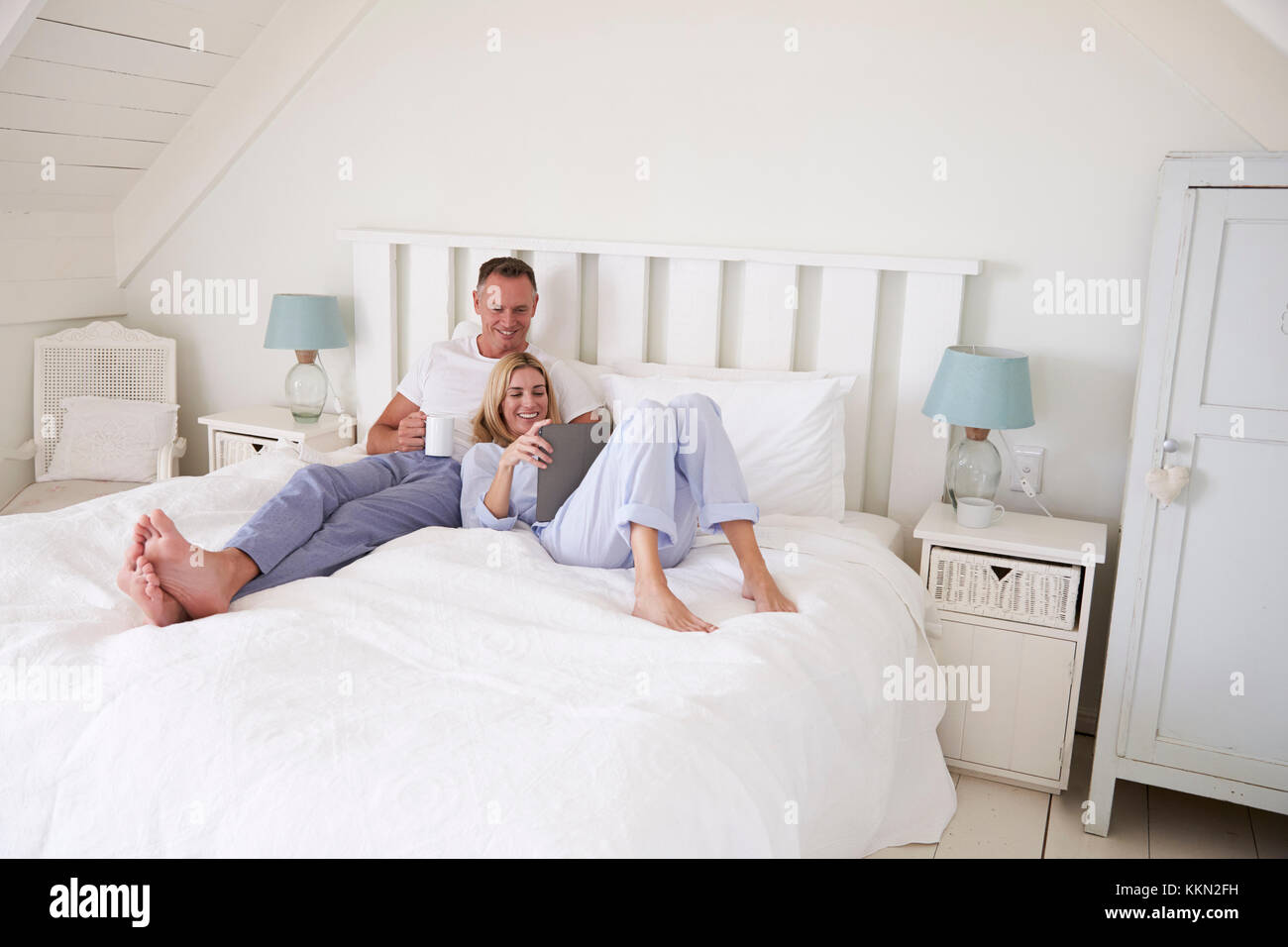 Coppia giacendo in letto guardando a tavoletta digitale insieme Foto Stock