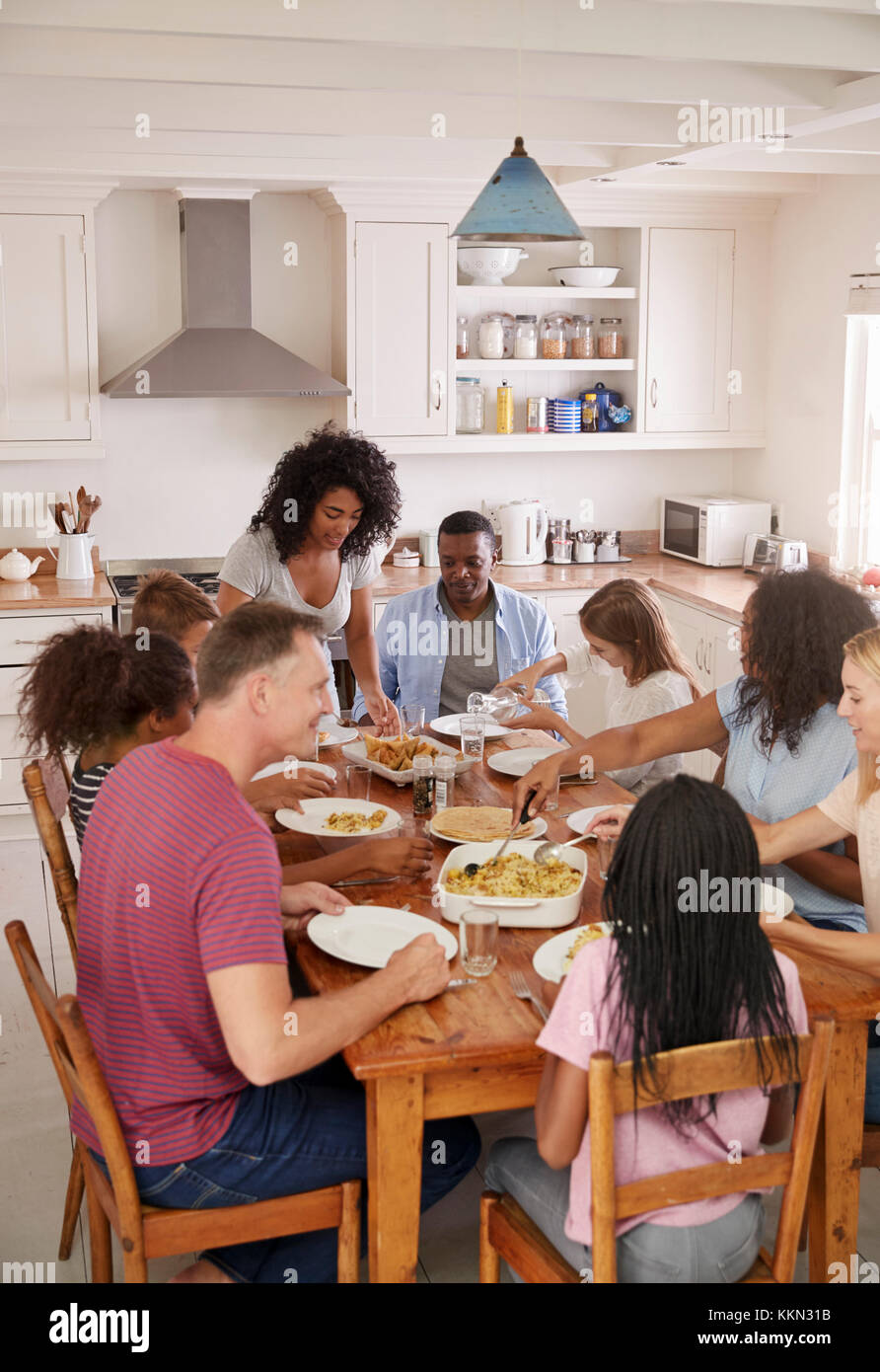 Due famiglie Godendo mangiando pasto a casa insieme Foto Stock