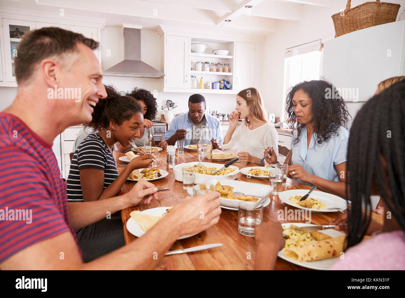 Due famiglie Godendo mangiando pasto a casa insieme Foto Stock
