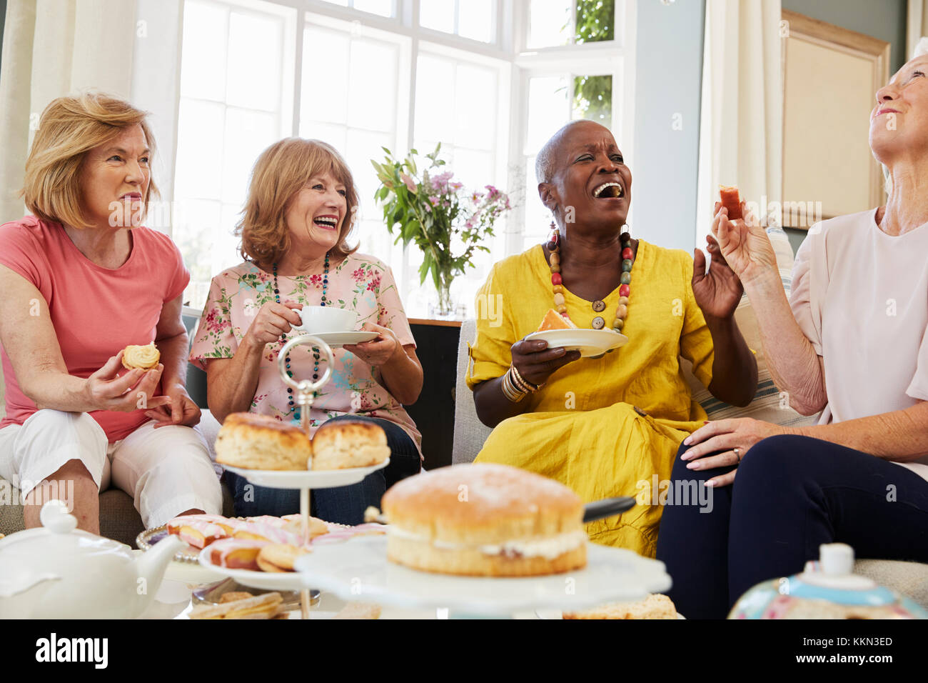 Femmina Senior amici gustando il tè del pomeriggio a casa insieme Foto Stock