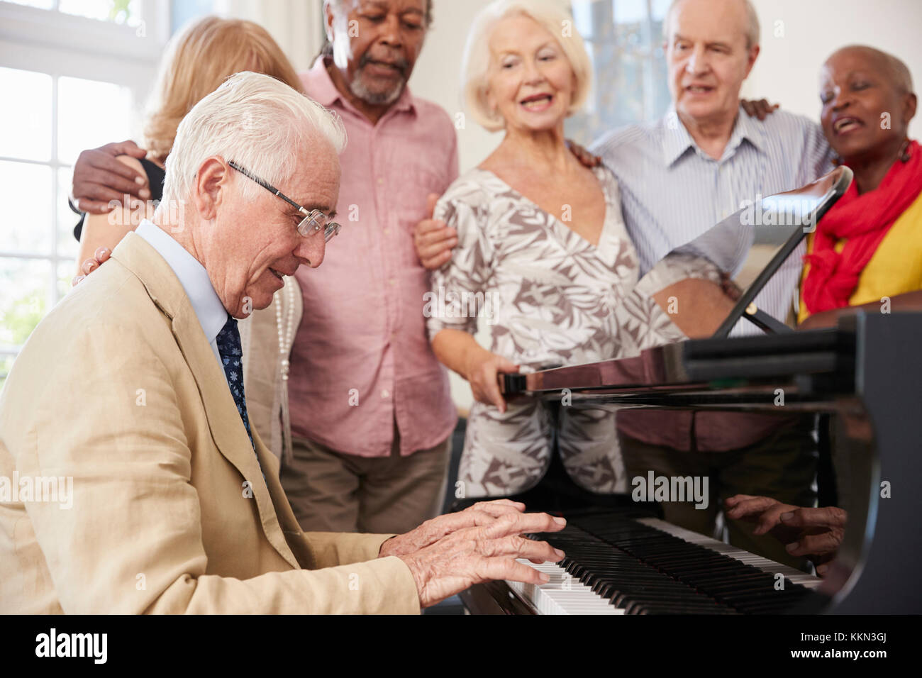Gruppo di anziani in piedi da pianoforte e canto insieme Foto Stock