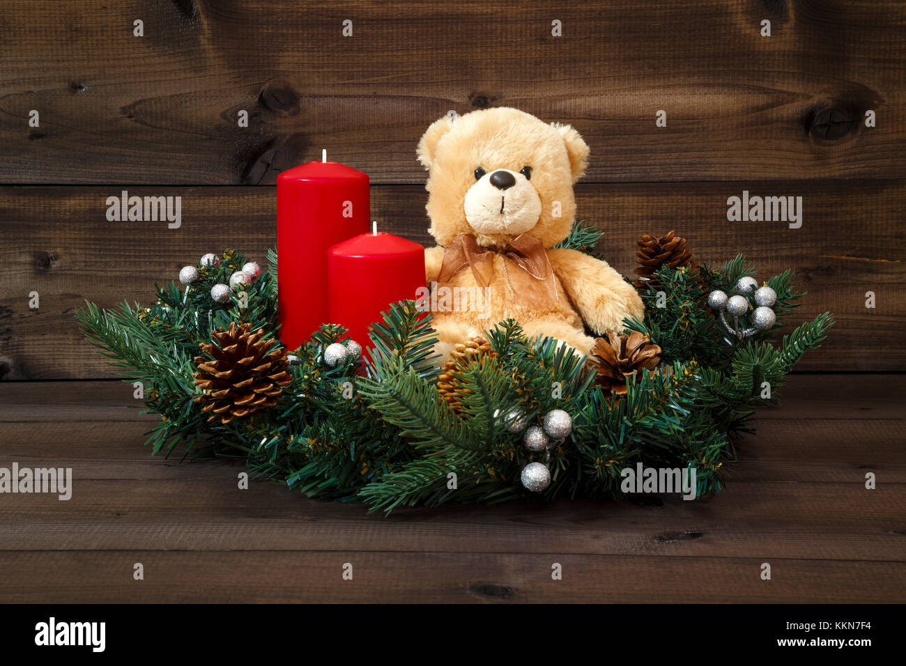 Decorate corona di Avvento con un orsacchiotto e due candele rosse su uno sfondo di legno. Foto Stock
