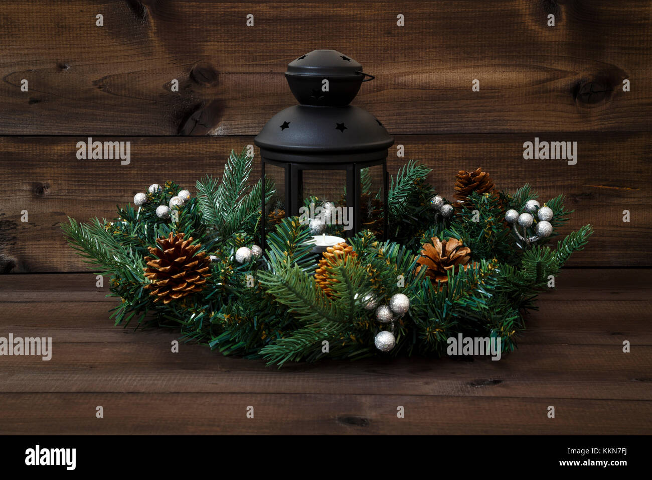 Decorate corona di Avvento con una lanterna nera con un tè luce su uno sfondo di legno. Foto Stock