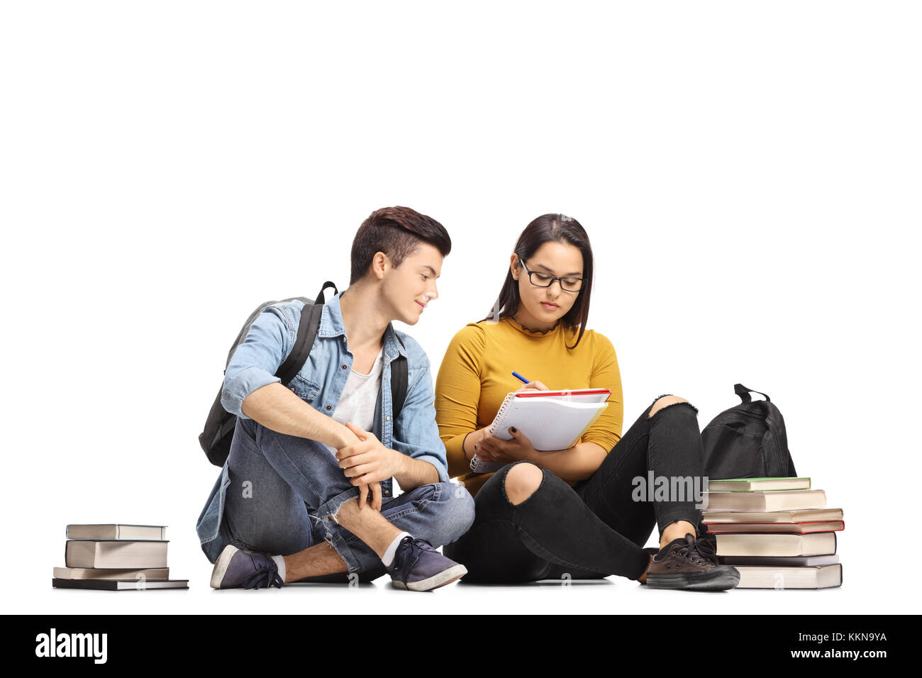 Teenage studenti seduti sul pavimento studiando insieme isolato su sfondo bianco Foto Stock