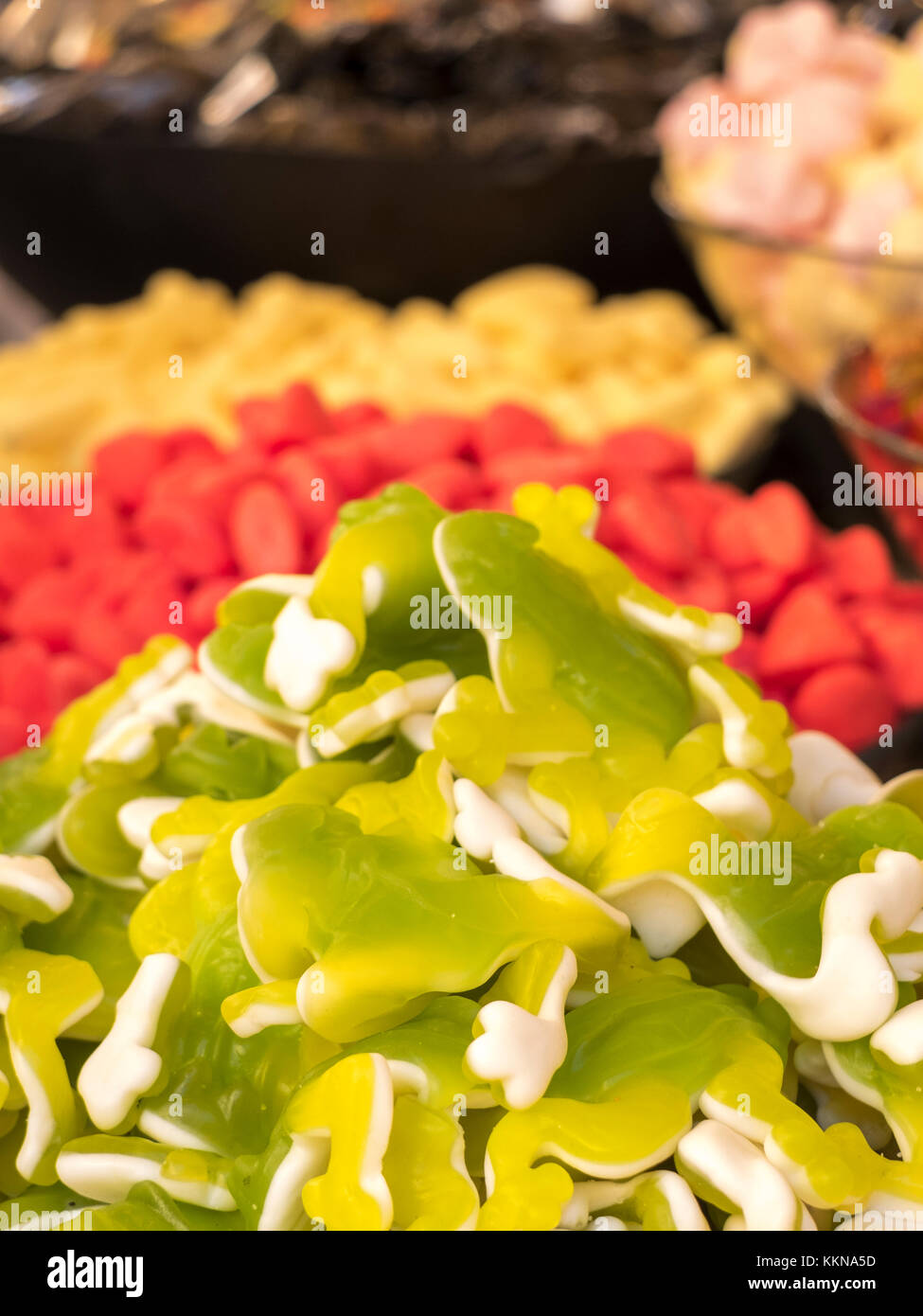 Variato candy ammassi in primo piano frutto gum caramelle gommose, verde e bianco su sfondo rosso e giallo caramelle di zucchero. Foto Stock