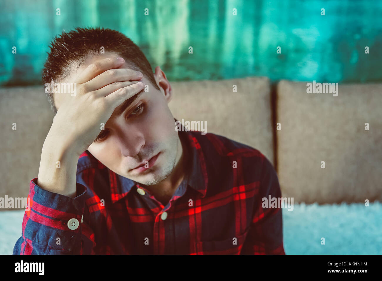 Profilo laterale ha sottolineato triste pianto giovane uomo seduto fuori tenendo la testa con le mani guardando giù. emozione umana sentimenti. in un cattivo umore. cefalea, testa Foto Stock
