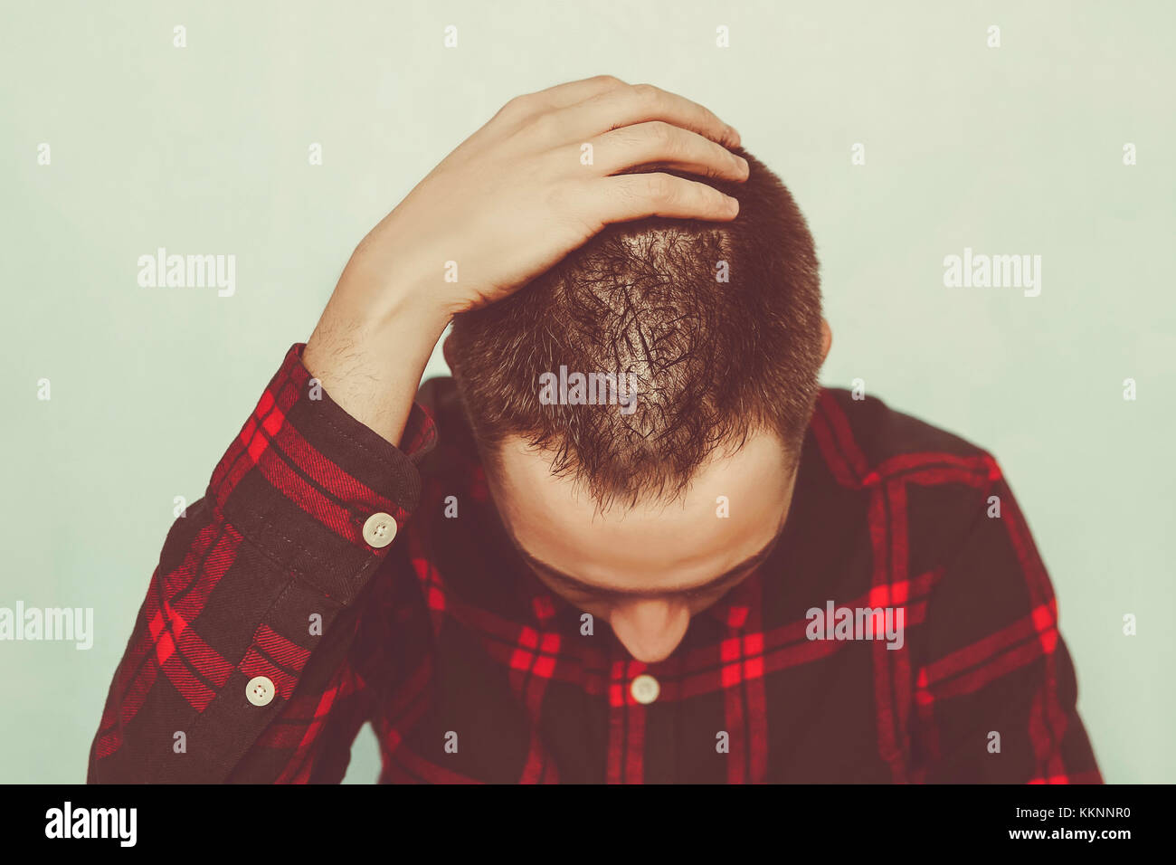 Un giovane uomo in una profonda depressione. concetto di dolore all'amore non corrisposto. Un uomo tiene una mano per la parte posteriore della testa. una triste condizione. disperazione Foto Stock