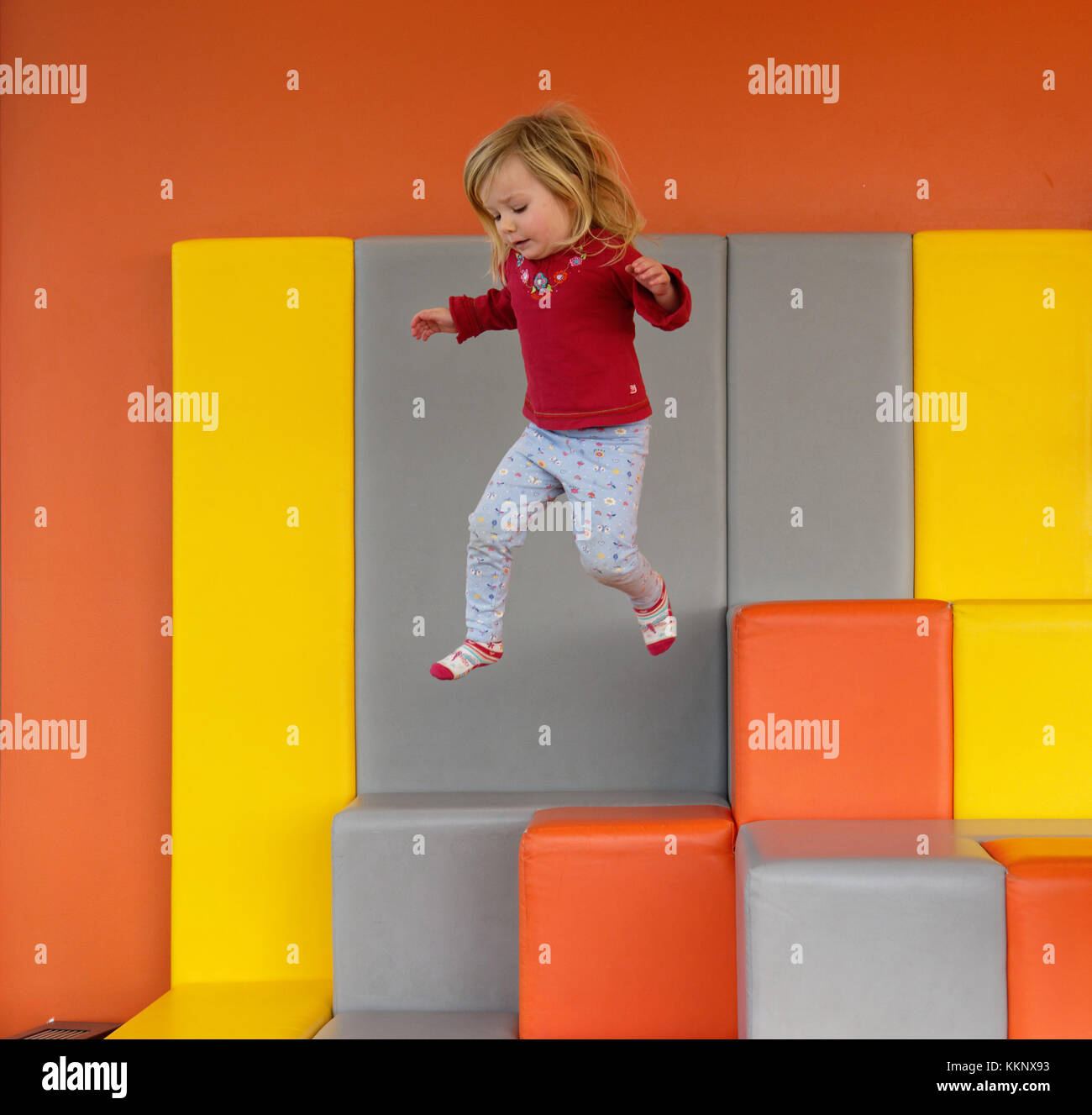 Una bambina di 3 anni) saltare in un imbottito per area di gioco Foto Stock