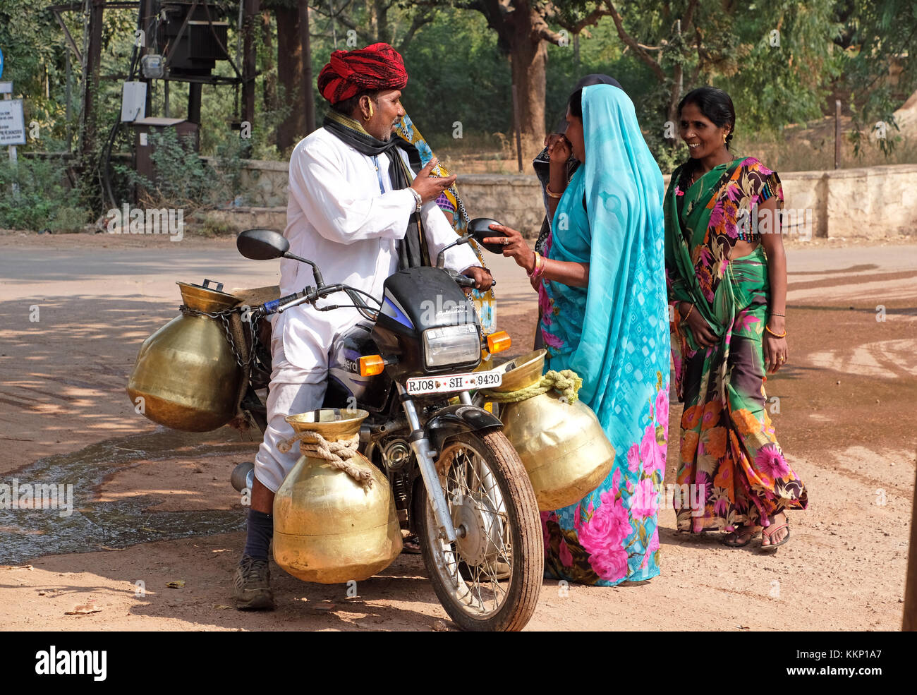Un uomo su una moto consegnare latte in grandi urne di metallo, Bundi,Rajasthan,l'India Foto Stock