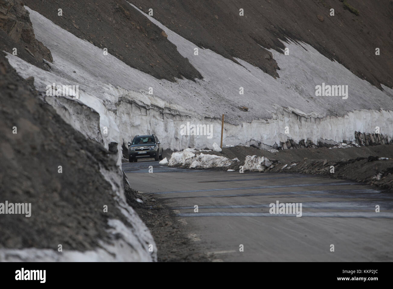 Una unità di auto lungo la strada di montagna delimitate da neve a col de la Bonette, Francia nel giugno 2017 Foto Stock