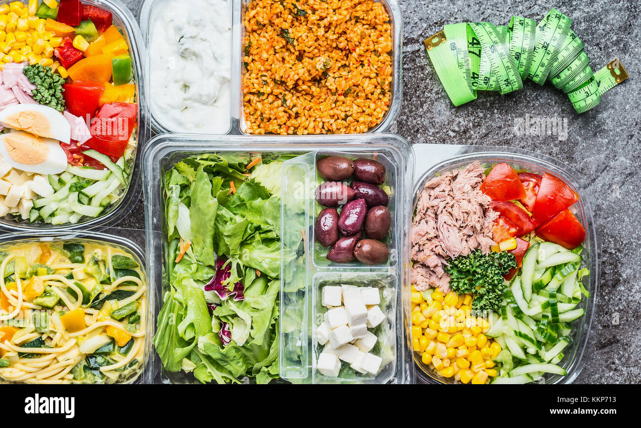 Varietà di dieta salutare il pranzo di scatole con insalata di verdure e nastro di misurazione. Contenitori per insalate in confezioni di plastica con nastro di misurazione, vista dall'alto. La dieta Foto Stock