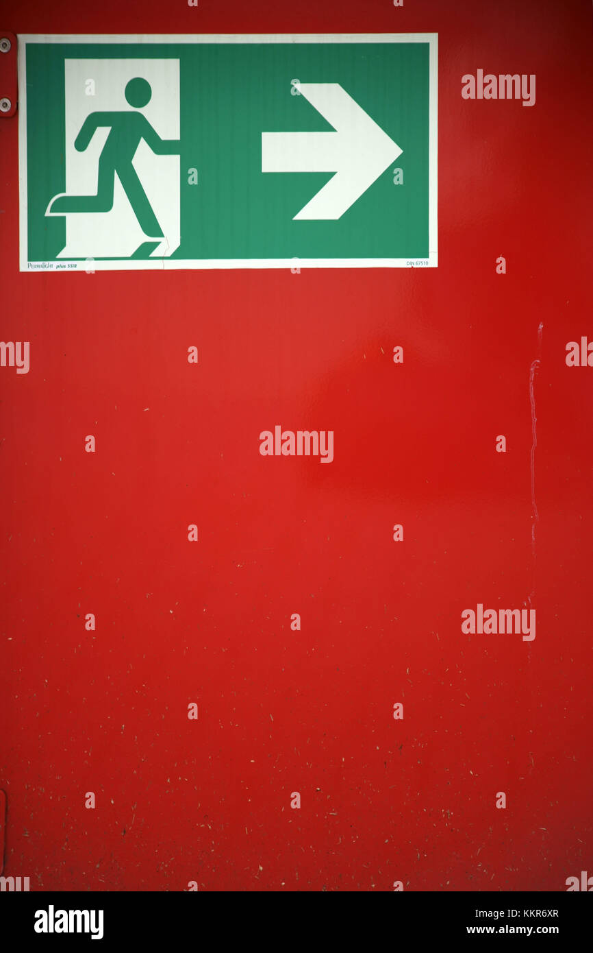 Cartello uscita di emergenza / via di fuga su un muro rosso, Foto Stock