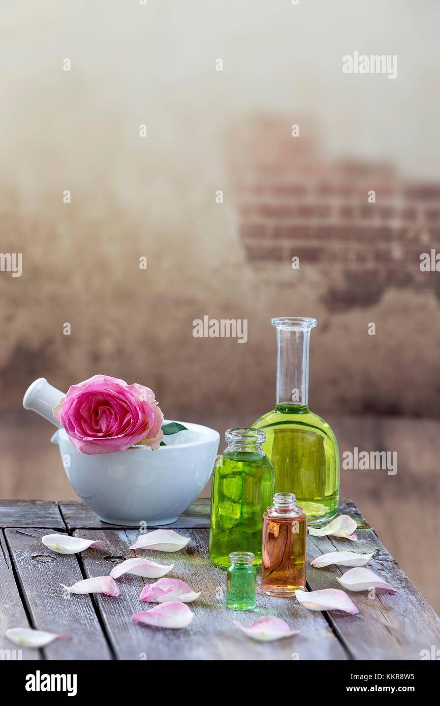 Spa e il concetto di benessere: preparazione di olio essenziale di rosa rose, bottiglia di tintura e di mortaio su una tavola di legno con tutte le parete vintage Foto Stock