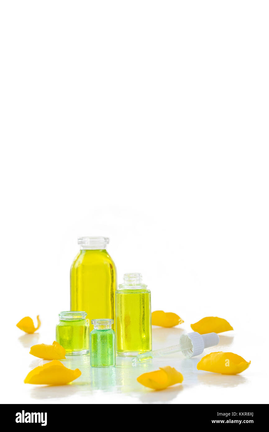 Una bottiglia di rosa olio essenziale di colore giallo con petali di rose sul whitebackground Foto Stock