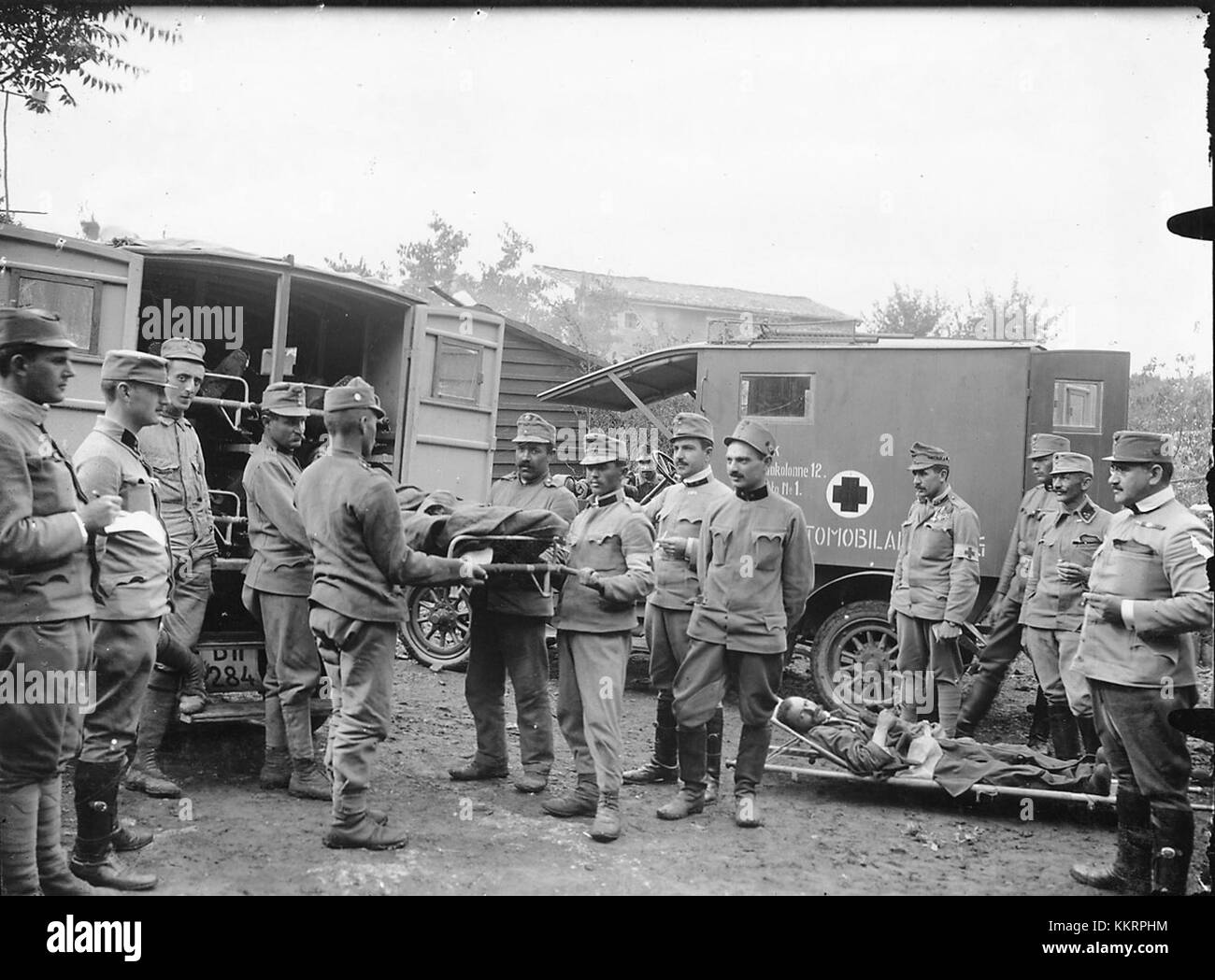 Questa immagine raffigura il carico di soldati feriti in ambulanze, probabilmente durante un conflitto, mostrando la risposta medica in tempo di guerra e gli sforzi per trasportare i feriti in sicurezza durante le operazioni di combattimento. Foto Stock