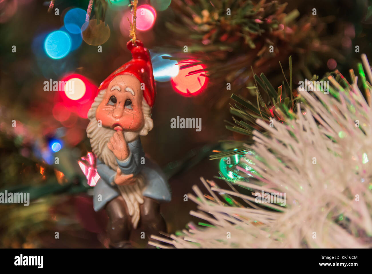 Un colorato closeup di un natale elf appeso a un albero decorato con una profondità di campo ridotta e incantevole al di fuori della messa a fuoco lo sfondo. Foto Stock