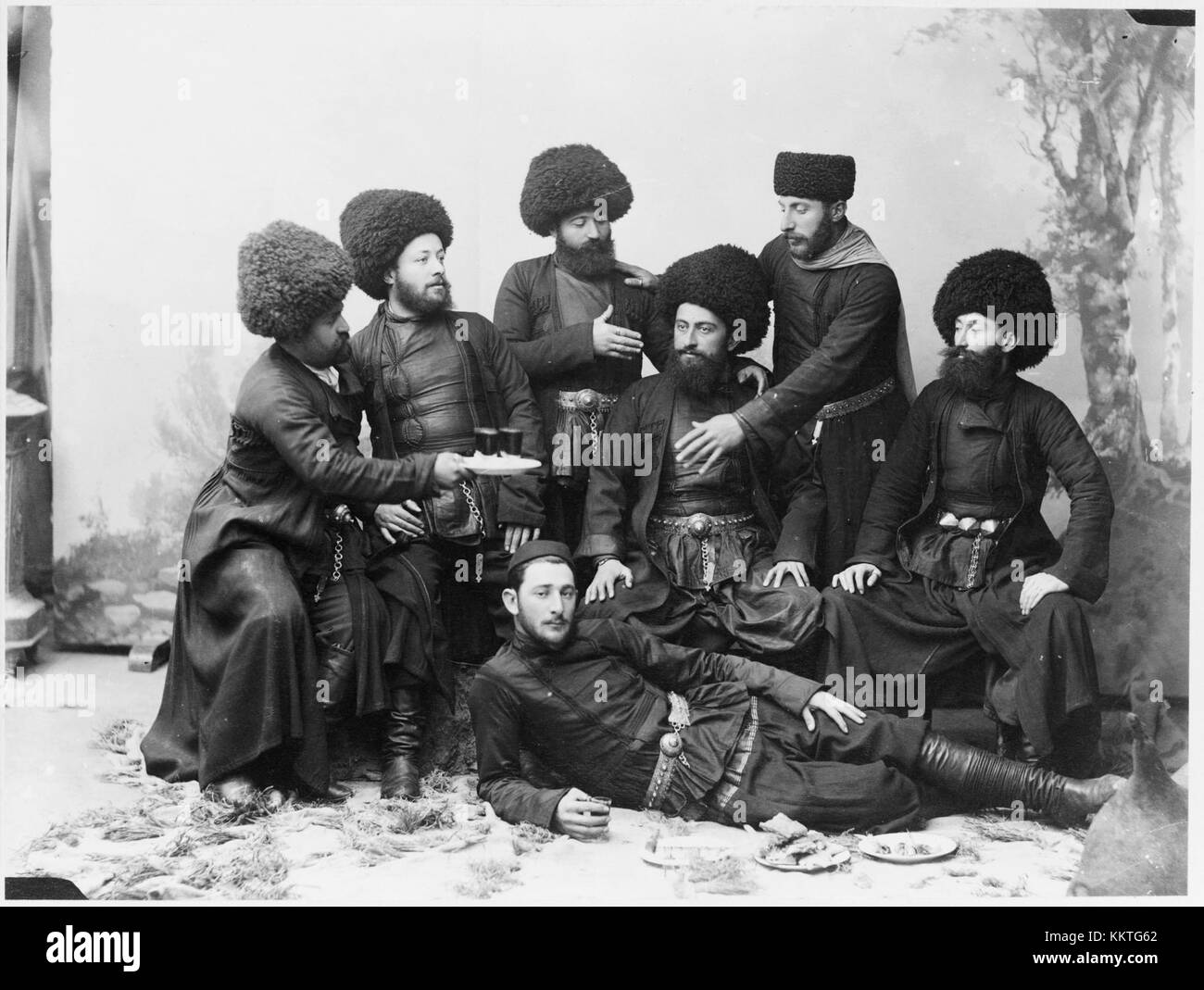 Una fotografia storica che mostra sette uomini in tradizionale abbigliamento cosacco, che si posa come a una festa nella Repubblica di Georgia. L'immagine riflette il ricco patrimonio culturale e le tradizioni storiche della regione. Foto Stock