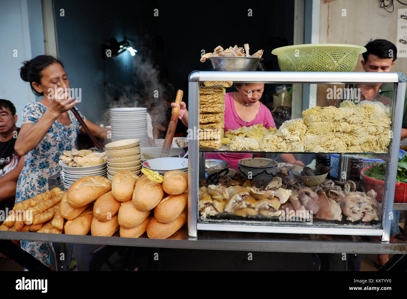 Ho chi minh city, Viet Nam, femmina fornitore wonton di cottura Zuppa di noodle al ristorante sul marciapiede, contatore alimentare con pasta, carne di maiale, pane, Vietnam Foto Stock