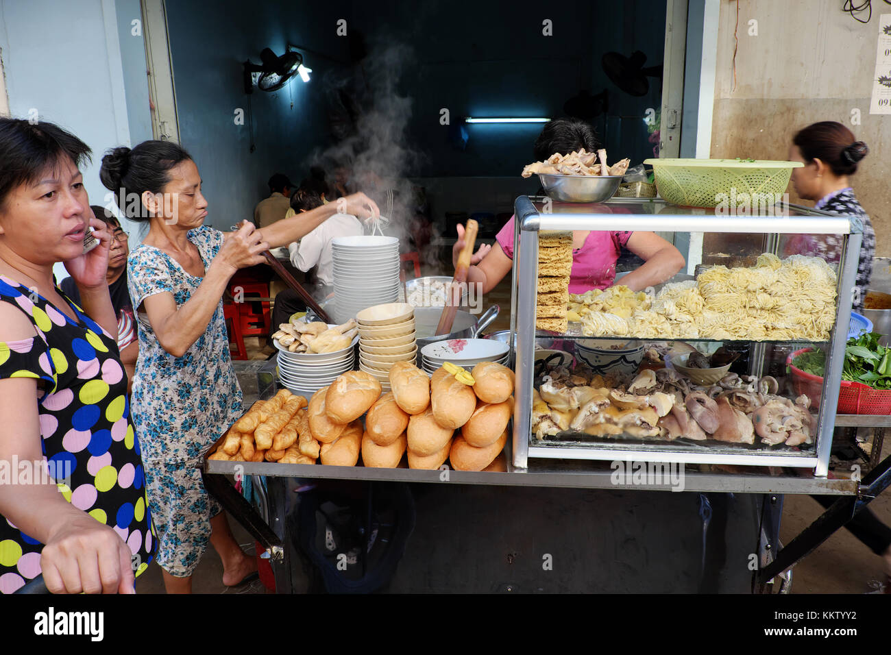 Ho chi minh city, Viet Nam, femmina fornitore wonton di cottura Zuppa di noodle al ristorante sul marciapiede, contatore alimentare con pasta, carne di maiale, pane, Vietnam Foto Stock