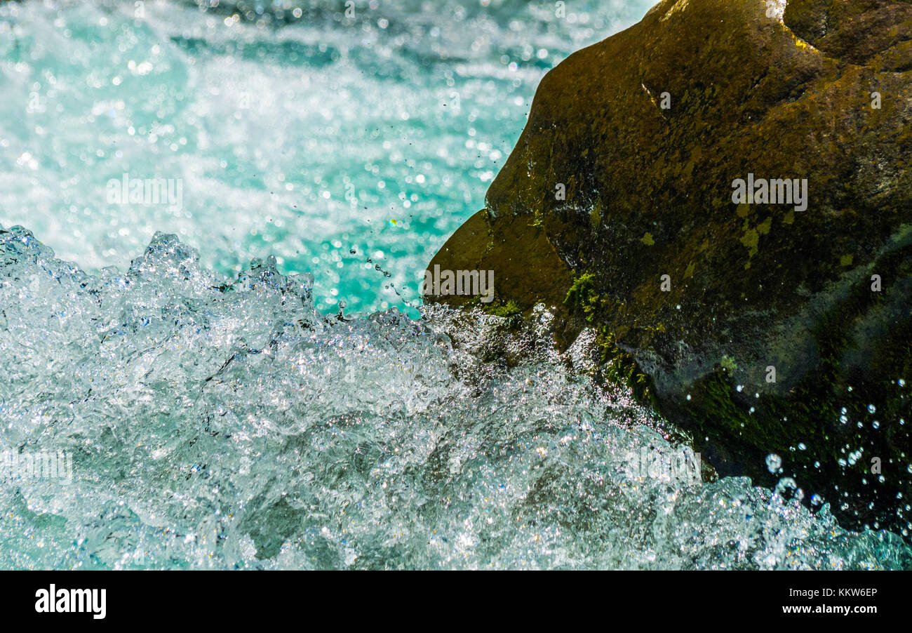 Spruzzi d'acqua contro una roccia bagnata Foto Stock