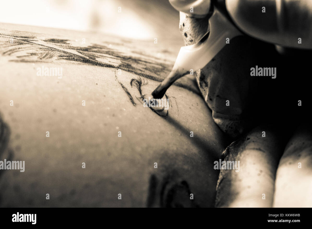 Un tatuaggio artista disegna un ritratto sulla pelle di una persona. Foto Stock