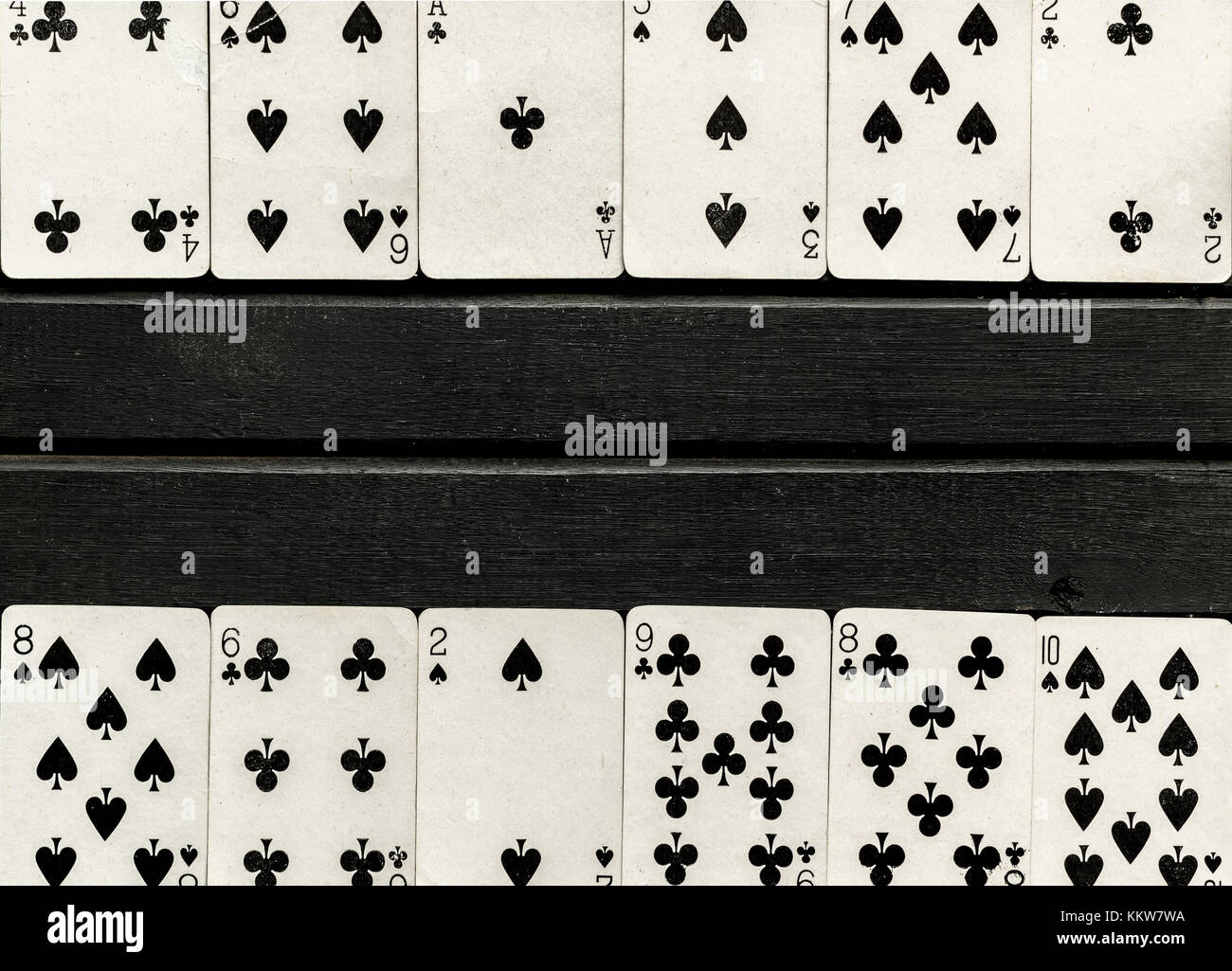 Mazzo di bianco e nero giocando a carte a faccia scoperta, nero su sfondo di legno, carte allineate sul bordo della cornice Foto Stock