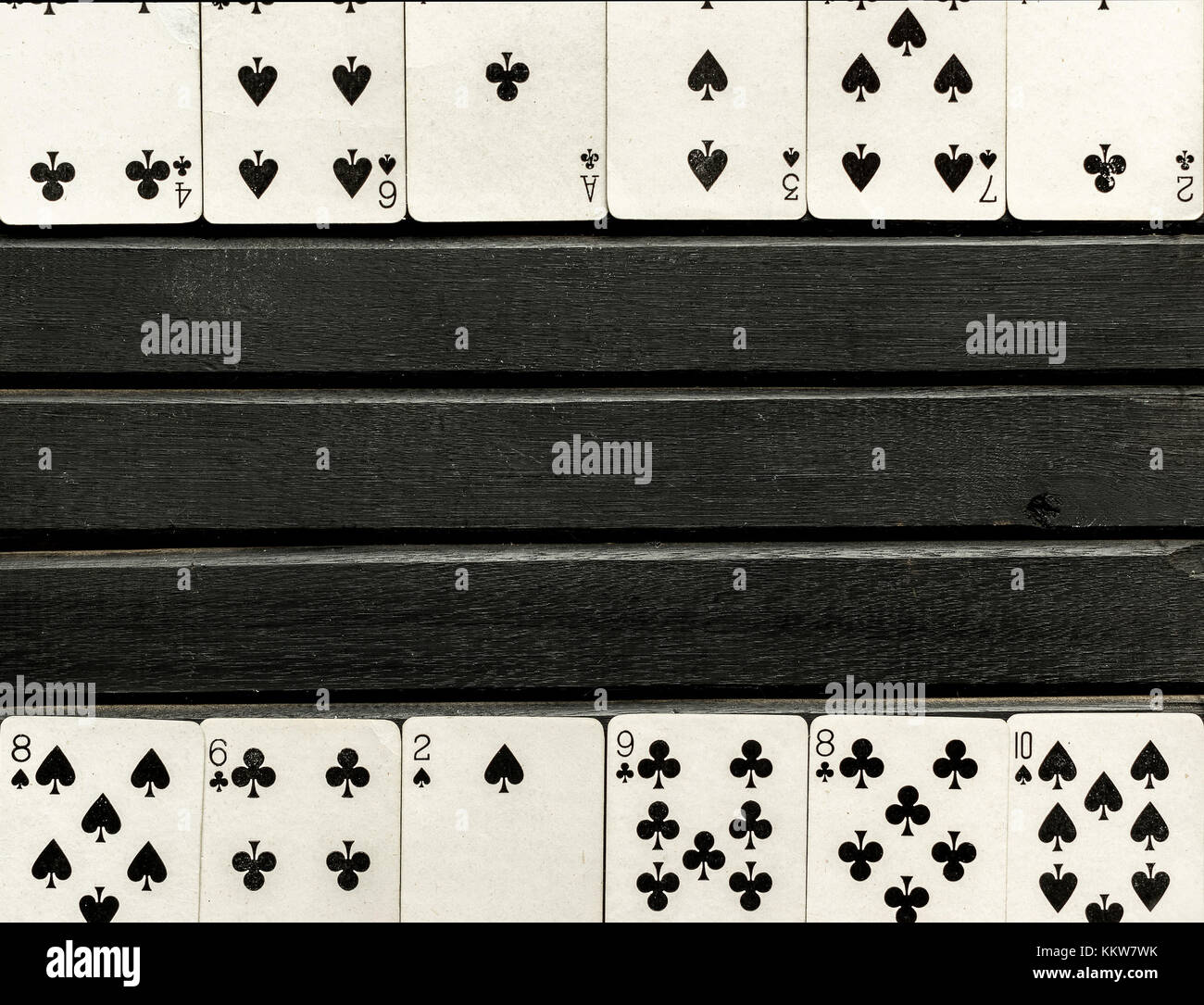 Mazzo di bianco e nero giocando a carte a faccia scoperta, nero su sfondo di legno, carte allineate sul bordo della cornice Foto Stock