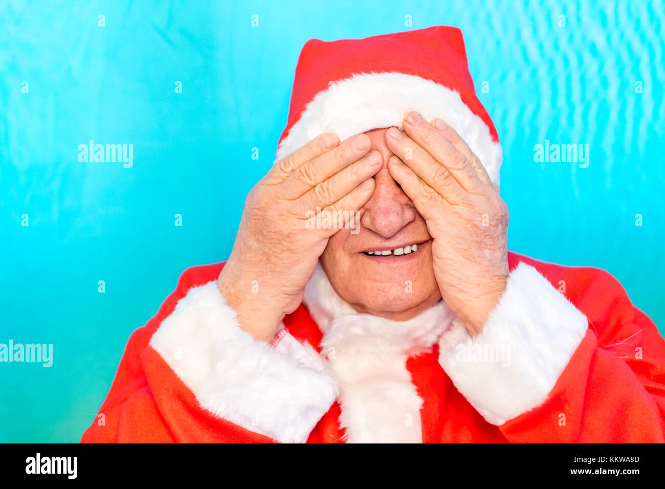 Il vecchio uomo che indossa Santa Claus costume che copre la sua gli occhi con le mani Foto Stock