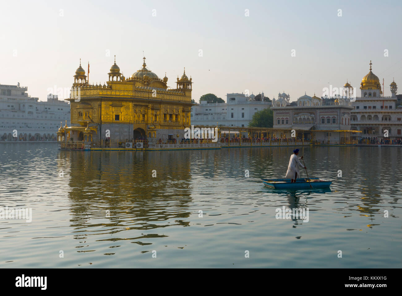 Punjabi Sikh guide uomo punt oltre l'uomo fatto piscina al tempio d'oro di Amritsar Punjab Foto Stock