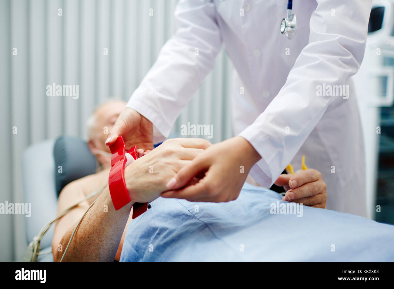 L'infermiera messa speciale apparecchiatura cardiologica intorno al polso del paziente prima di esaminare il cuore Foto Stock