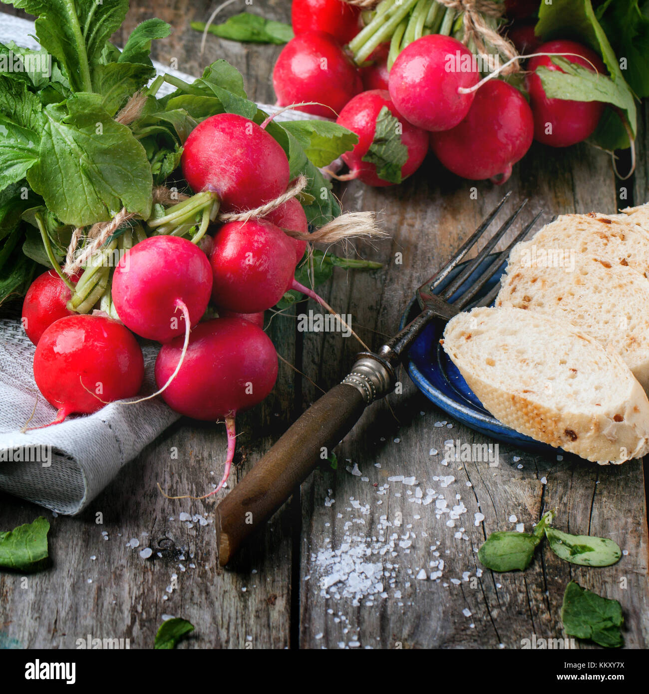 Fresche ravanelli bagnato con forcella vintage, sale marino e pane su un vecchio tavolo in legno. immagine quadrata Foto Stock