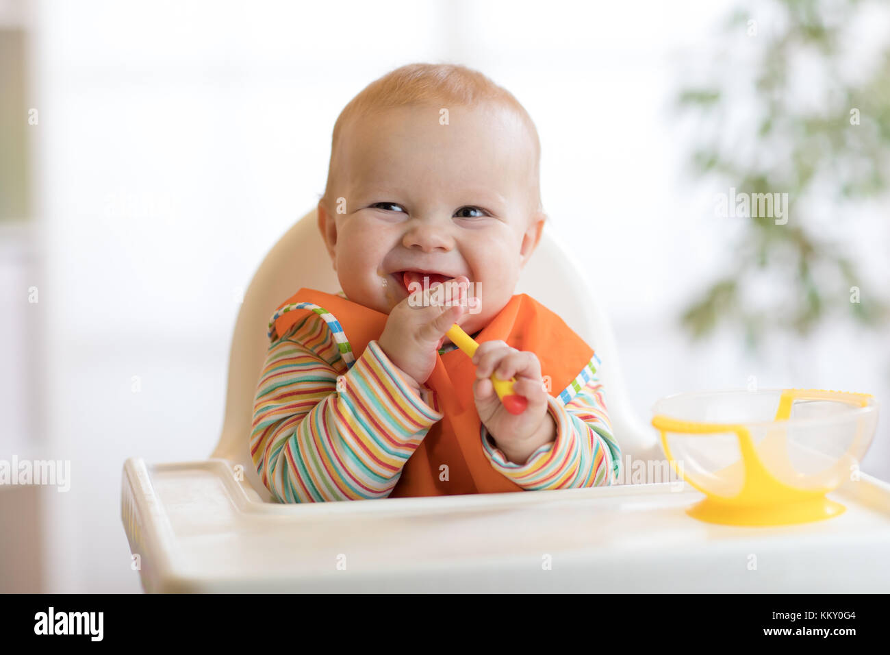 Happy baby boy in attesa di cibo con cucchiaio a tavola Foto Stock