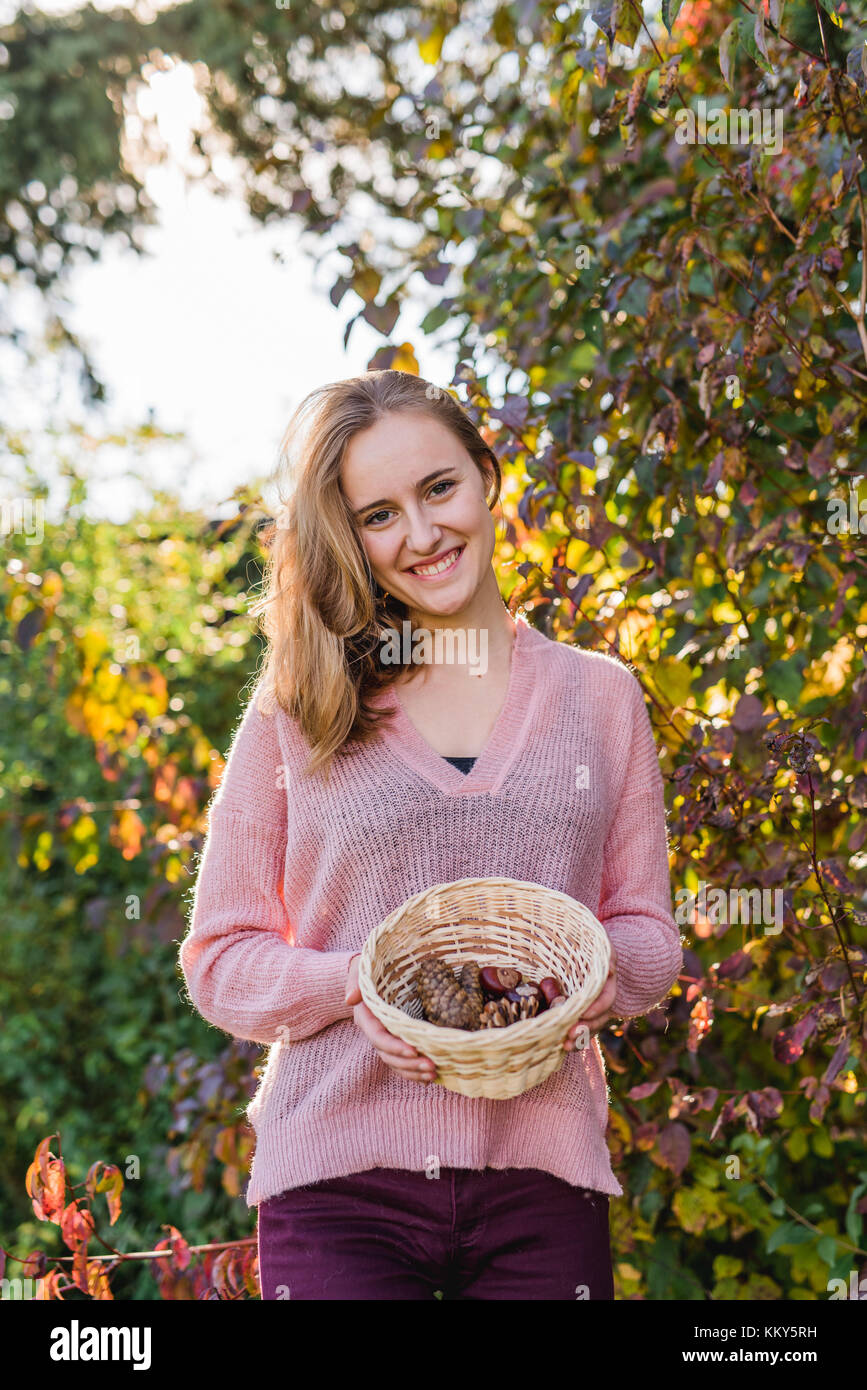 Giardino, giovane donna con cesto di raccolta di materiali naturali, Foto Stock