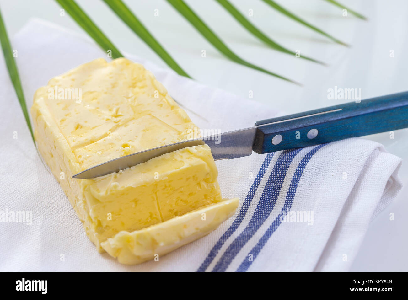 Burro. fetta di burro fresco affettato burro sul piatto su bianco e lo sfondo di colore verde Foto Stock