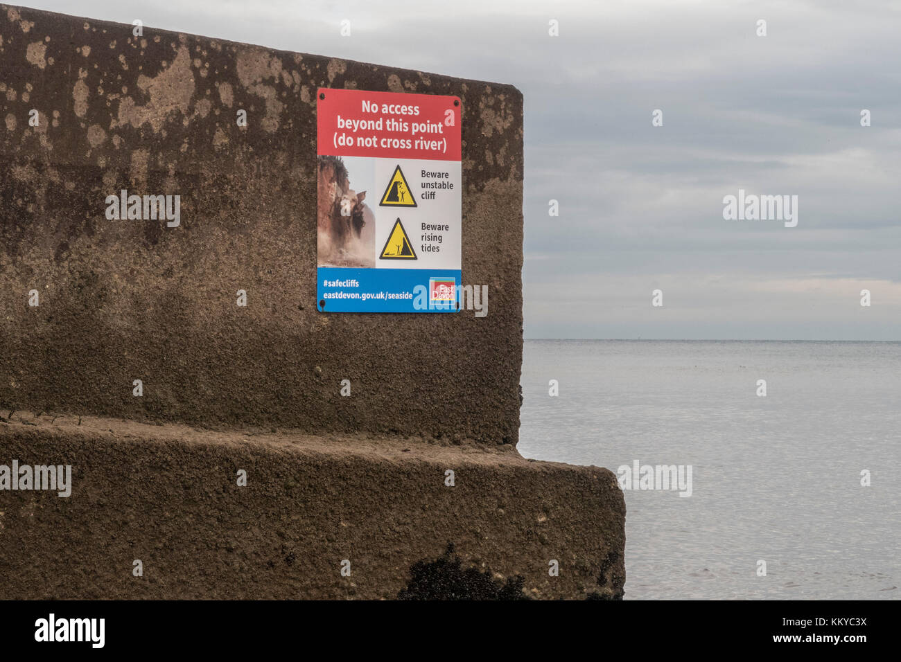 Segnale di avvertimento sul lungomare a Sidmouth, non cross river, instabile cliff,attenzione crescente delle maree. Foto Stock