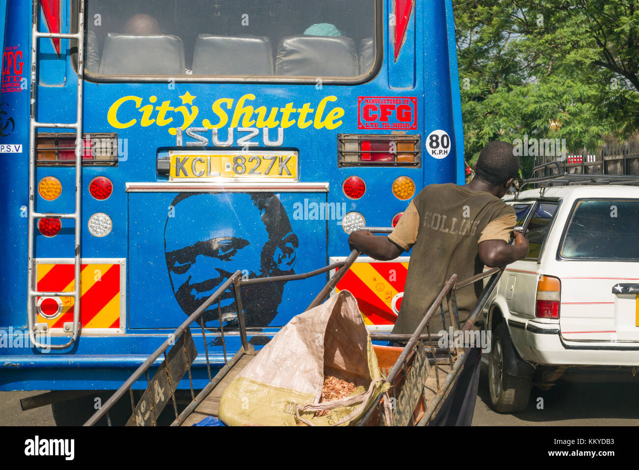 Un uomo con il camion di tenta di passare davanti a un bus con un dipinto del Presidente Uhuru Kenyatta sul retro, Nairobi, Kenia Foto Stock