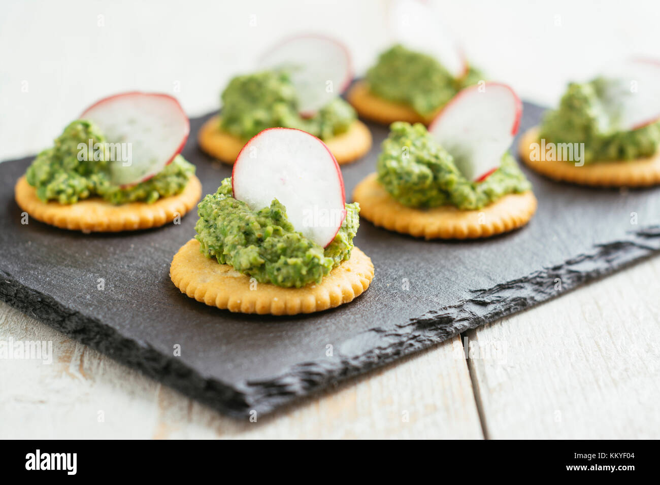 Il segnale di PEA e ravanelli verdi pesto spalmato su cracker Foto Stock