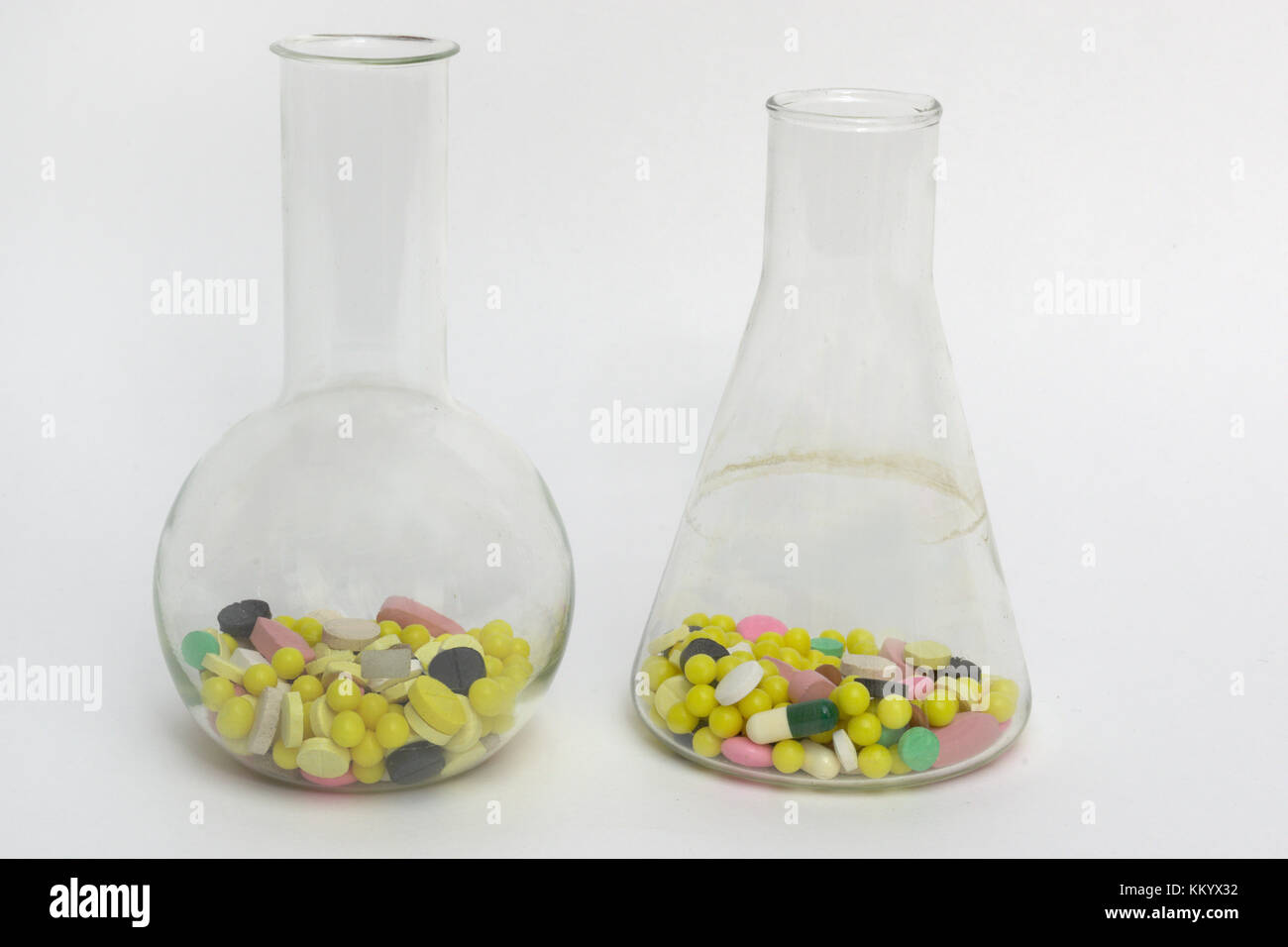 Vetro da laboratorio: rotonda e conica di fondo piatto e lungo collo boccette, riempita di pillole colorate e confetto Foto Stock