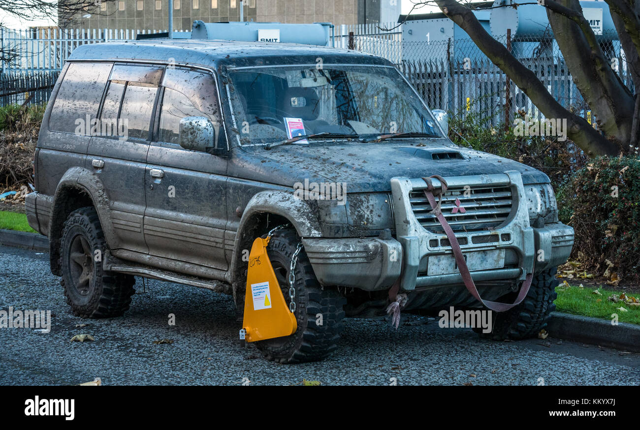 Il fango opener Mitsubishi Shogun 4x4 car invasata con biglietti per il parcheggio e a morsetto di bloccaggio di ruota, Leith, Edimburgo, Scozia, Regno Unito Foto Stock