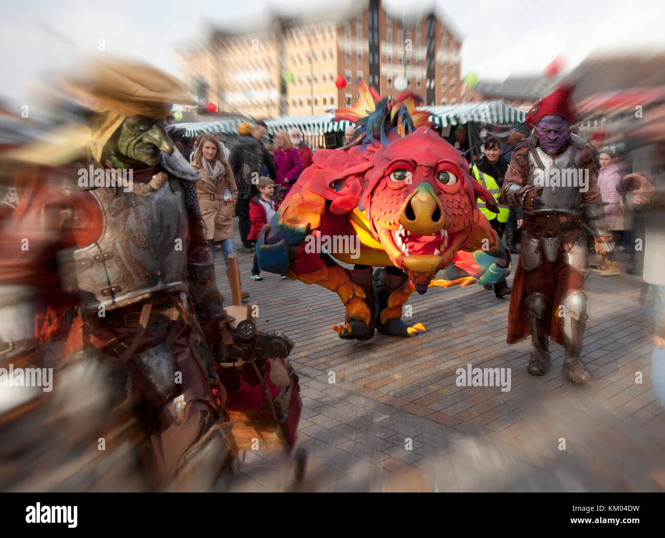 Un pet dragon guidato da due mascherato e blindato di supervisione in stile tolkein è passato a led curiosi un mercatino di natale in bacini di gloucester, Regno Unito Foto Stock