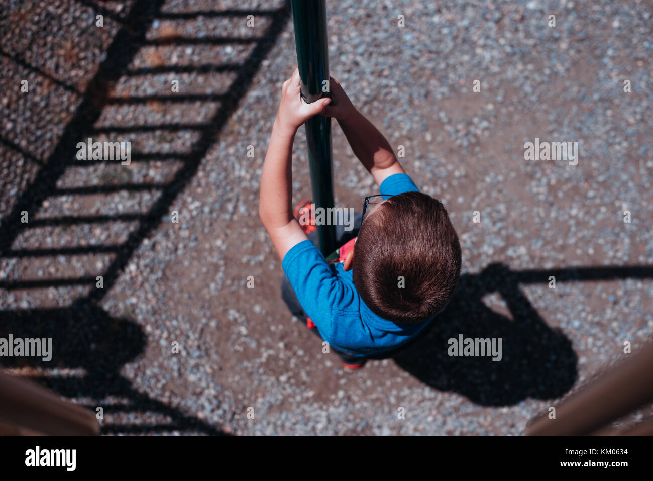 Un bambino scorre verso il basso di un polo di scorrimento in un parco giochi. Foto Stock