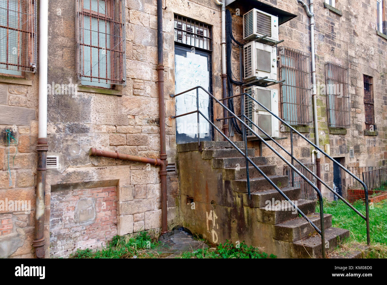 Finestra di griglie e murate e imbarcati porte in entrata posteriore di tenements in Govan, Glasgow, Scozia Foto Stock