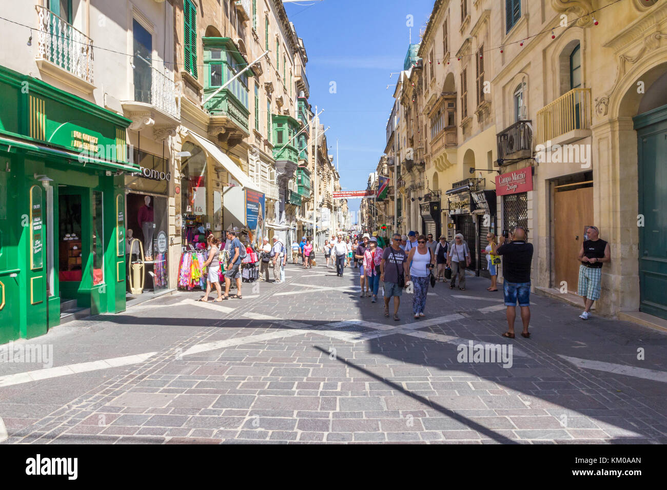 I turisti passeggiano lungo Triq II Merkanti, strada pedonale a La Valletta, Malta Foto Stock