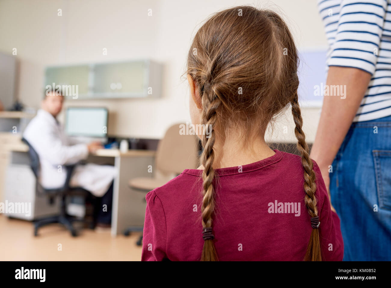 Spaventata Bambina entrando in ufficio medici con MOM Foto Stock