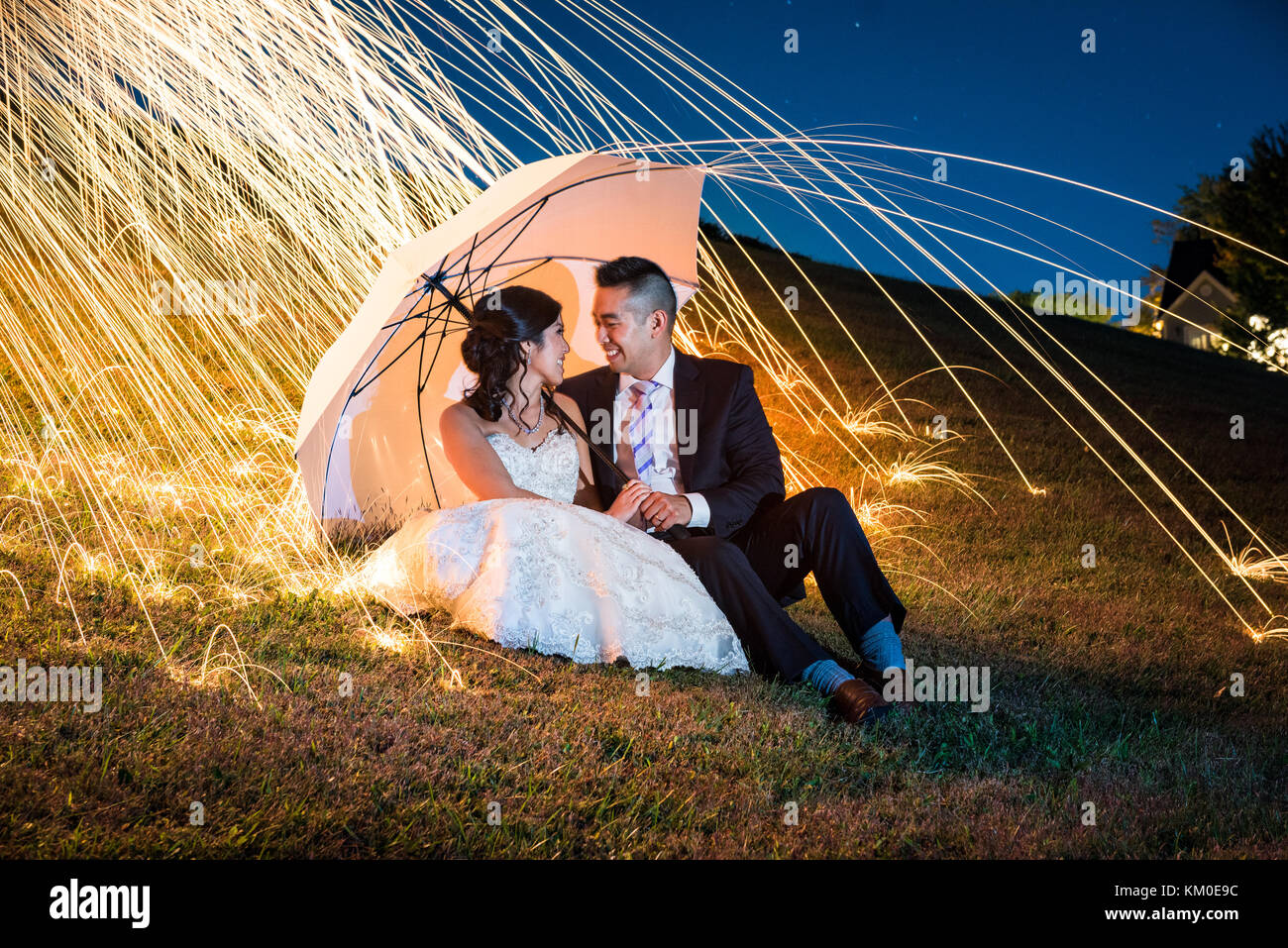 Creative con lunghi tempi di esposizione di pittura di luce con la sposa e lo sposo ritratti dopo un ricevimento di nozze. Foto Stock