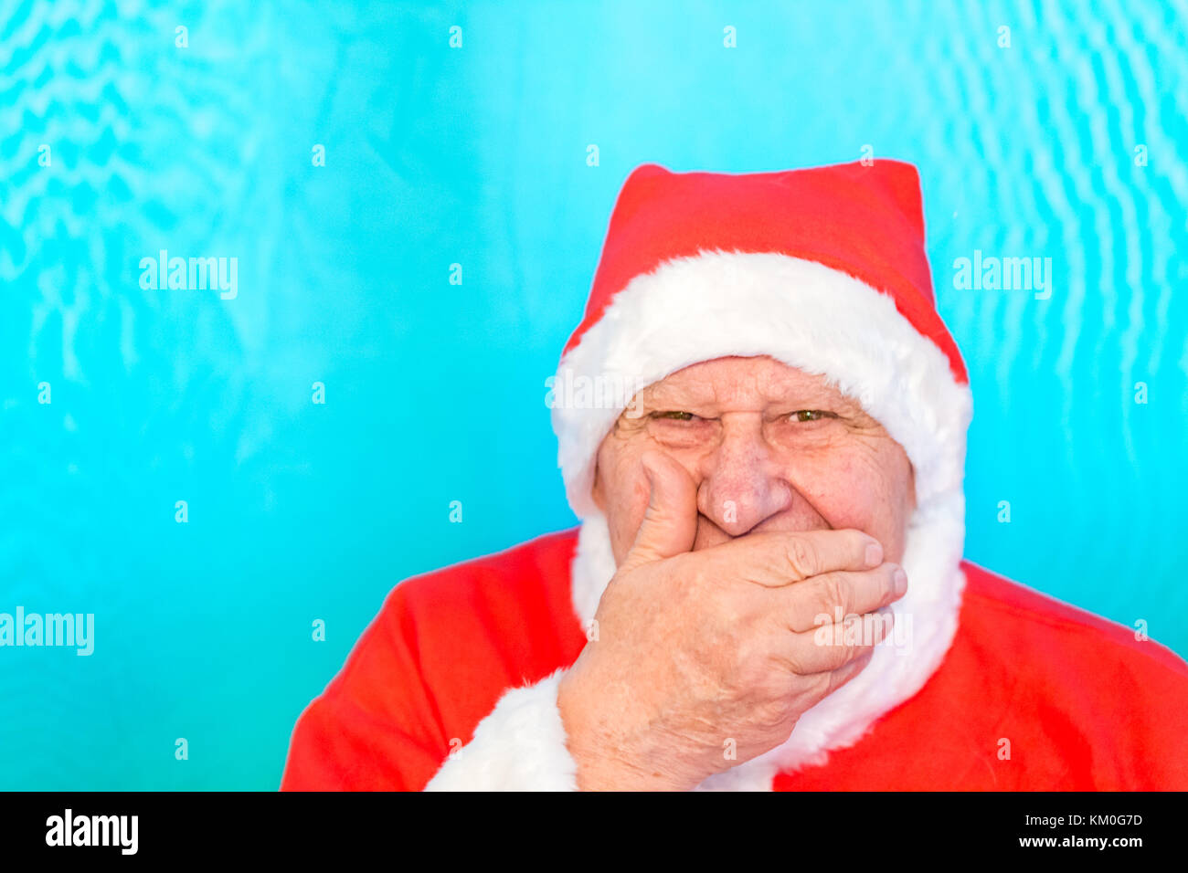 Il vecchio uomo che indossa Santa Claus costume che copre la bocca con la mano Foto Stock