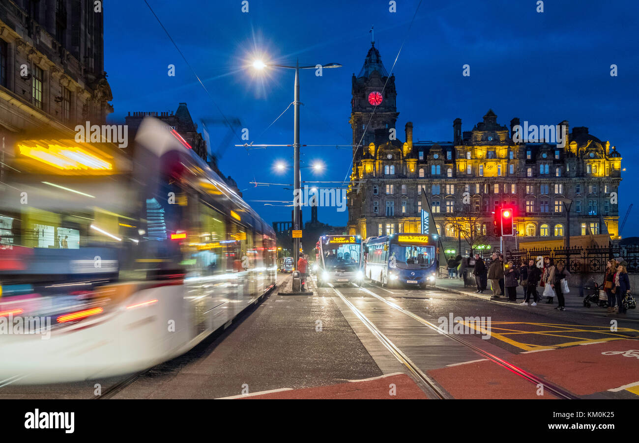Vista notturna di Princes Street con tram e autobus e Balmoral Hotel sul retro di Edimburgo, Scozia, Regno Unito. Foto Stock